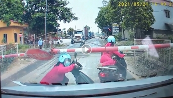 nguoi phu nu co dua chiec xe may vuot qua thanh barie mac doan tau gan toi