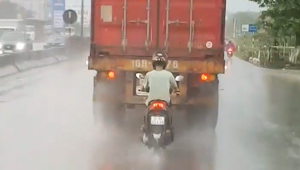 Camera giao thông: Tài xế xe máy liều lĩnh bám sát đuôi xe container để trú mưa